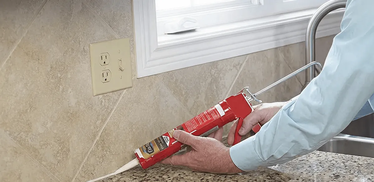 Handyman applying caulk along a kitchen backsplash and countertop seam in Austin, TX