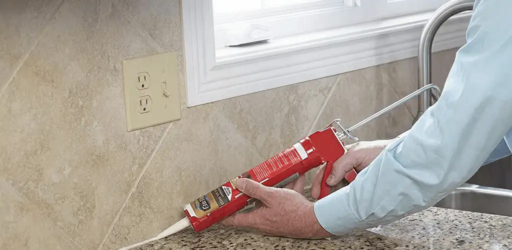Handyman applying caulk along a kitchen backsplash and countertop seam in Austin, TX