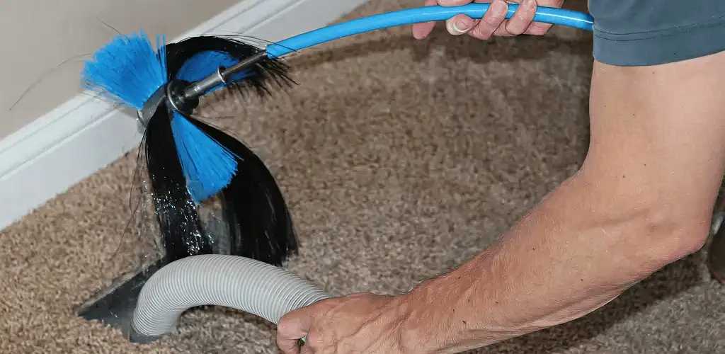 Dryer vent cleaning technician brushing lint from a vent line in Austin, TX