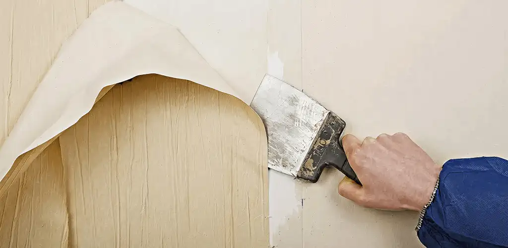 Handyman removing wallpaper with a scraper for wall preparation in Austin, TX