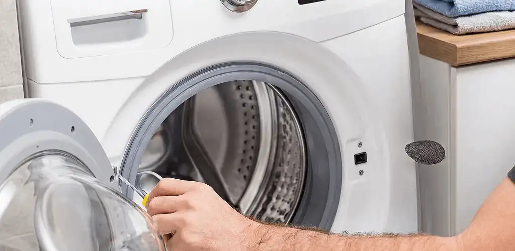 Handyman repairing a front-load washing machine and inspecting the drum in Austin, TX