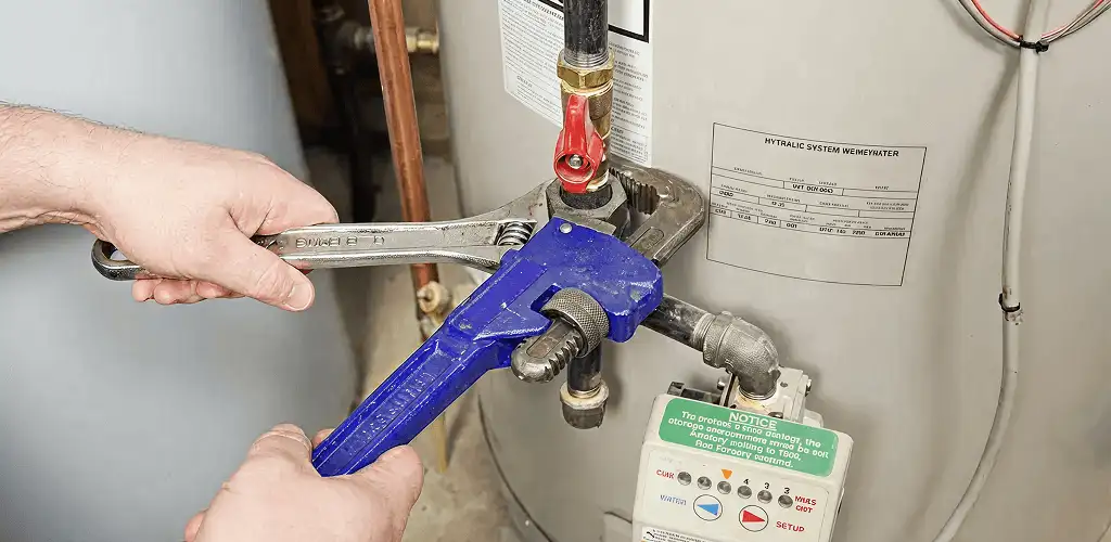 Water heater repair technician tightening the shutoff valve and supply line in Austin, TX